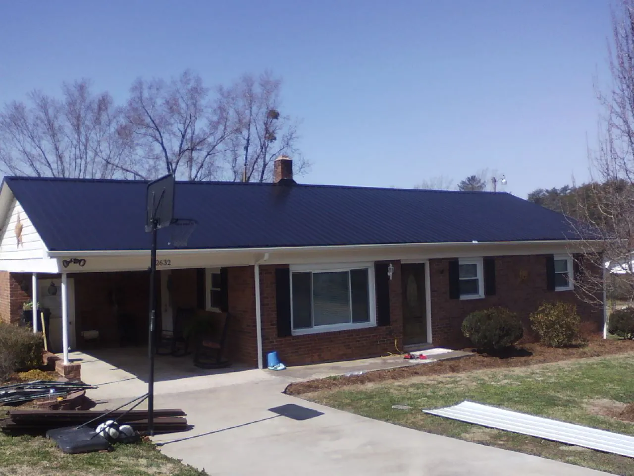 Finished dark blue metal roof on a brick ranch with a carport in Atglen