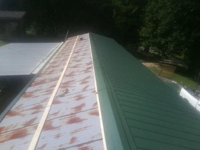 Old rusted panels beside newly installed green metal roofing — Wind Damage Roof Repair by Roofing Brothers in Atglen