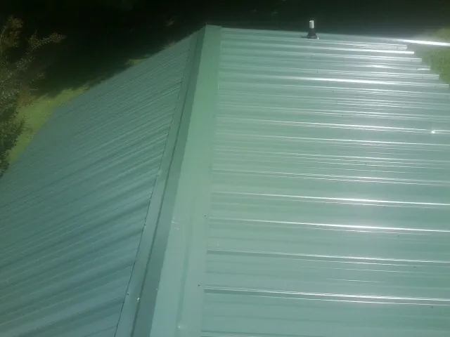 New green metal panels meeting at the ridge of a roof — Flat Roof Repair work by our crew in Atglen