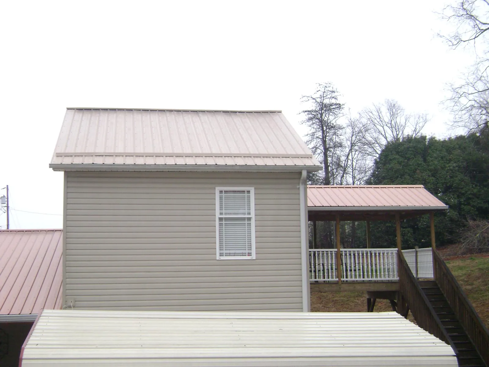 Tan metal roofs on a two story addition and attached porch, from a Roof Replacement job in Atglen