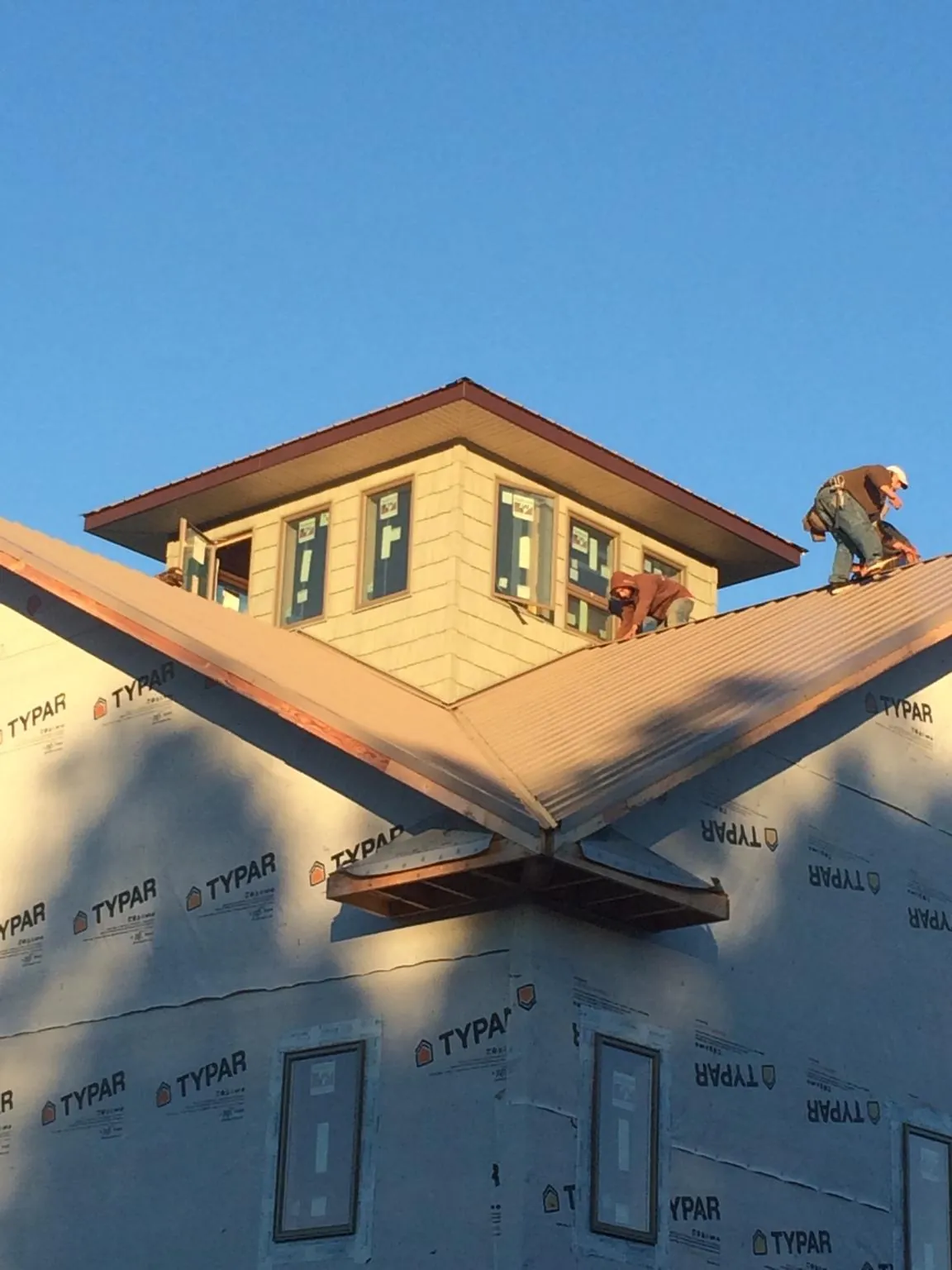 Roofers working around a rooftop cupola on a new metal roof at sunset — Roof Waterproofing in Atglen by Roofing Brothers